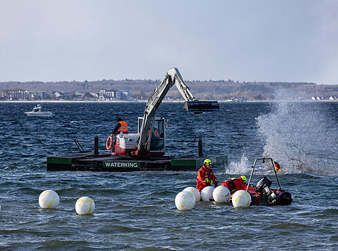 Ein Schwimmbagger arbeitet in der Nähe eines gestrandeten Buckelwals. Ein Schwimmbagger arbeitet in der Nähe eines gestrandeten Buckelwals.