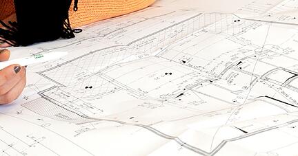 Eine Bauzeichnerin vor einem Bauplan. Die Bauindustrie fordert bessere digitale L&ouml;sungen f&uuml;r die Verwaltung.