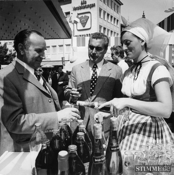 Weinverkostung aus der Hand einer Südfranzösin im costume traditionel des femmes biterroises. Industrie-und Handelskammer-Repräsentanten am Weinstand in der Fußgängerzone Fleiner Straße. Zum zehnjährigen Bestehen der Jumélage Béziers-Heilbronn 1975  werden in der Innenstadt französische Spezialitäten angeboten.