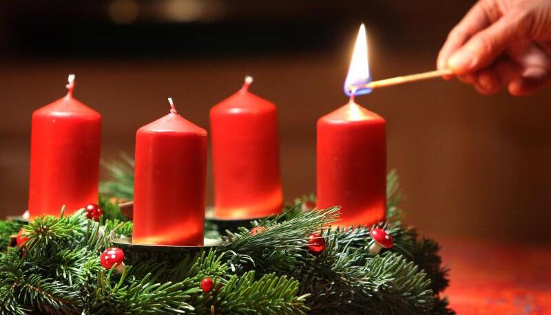 Eine Frau entzündet eine Kerze auf einem Adventskranz. 2023 ist das erst ab dem 3. Dezember möglich. Eine Frau entzündet eine Kerze auf einem Adventskranz. 2023 ist das erst ab dem 3. Dezember möglich.