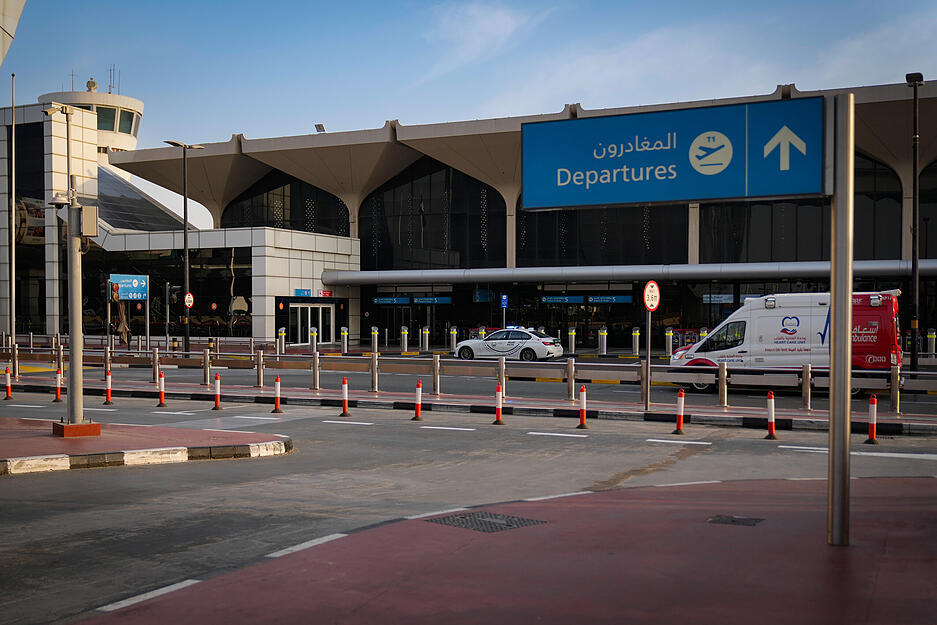 Ein Polizeifahrzeug und ein Krankenwagen stehen auf der Stra&szlig;e vor dem Abflufterminal des internationalen Flughafens von Dubai, der nach seiner Schlie&szlig;ung menschenleer ist.