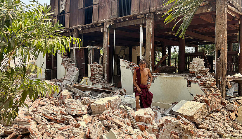 Ein buddhistischer Mönch steht in den Trümmern eines beschädigten Gebäudes in einer Klosteranlage nach einem Erdbeben in Myanmar.