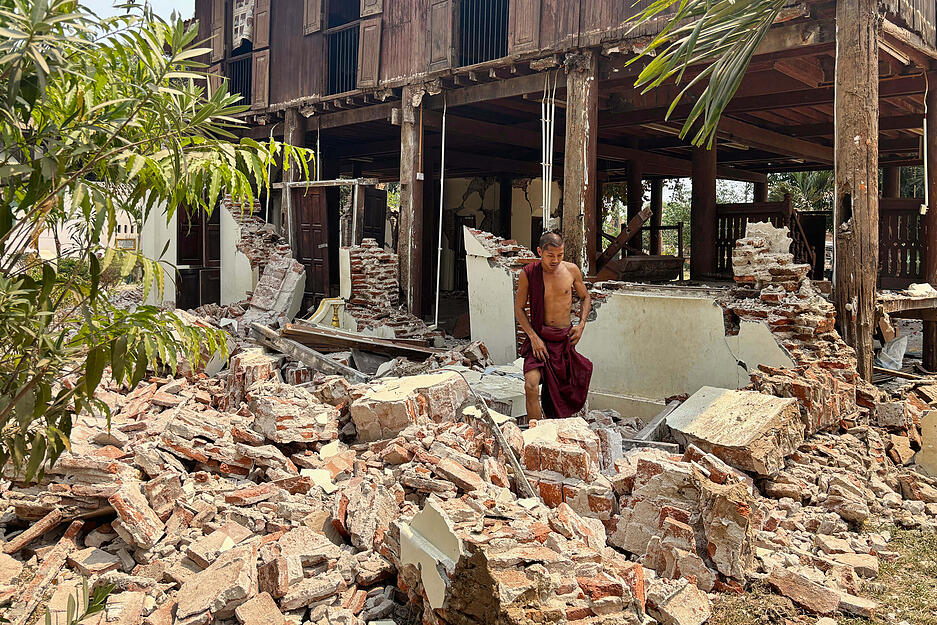 Ein buddhistischer Mönch steht in den Trümmern eines beschädigten Gebäudes in einer Klosteranlage nach einem Erdbeben in Myanmar.
