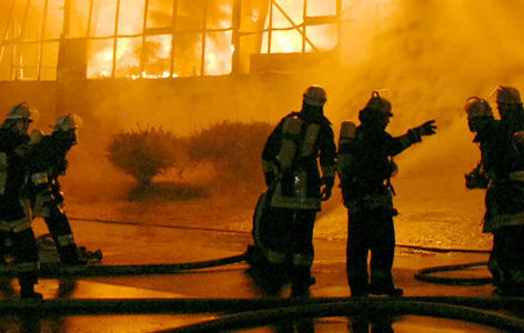 ARCHIV - Feuerwehrleute stehen vor einer brennenden Lagerhalle in Essen (Archivfoto vom 08.04.2009). "Löscheinsätze können wie Saunagänge sein", sagt ein Notfalltrainer von der Berliner Feuerwehr. Die Kollegen haben es bei Bränden mit hohen Temperaturen und einer starken Luftfeuchtigkeit zu tun. Die Schutzkleidung vermindert das Hitzeempfinden und kann so zur tödlichen Falle werden. Geplant ist nun im Rahmen des Verbundprojektes "FeuerWhere" der Einsatz eines drahlosen Sensornetzwerkes. Am Laptop kann so der Einsatzleiter die Körperfunktionen seiner Leute überwachen und sie im Notfall sofort zurückrufen. Foto: Armin Thiemer dpa (zu dpa-Korr-Bericht: "Funkende Minicomputer als Lebensretter" vom 14.04.2009) +++(c) dpa - Bildfunk+++ ARCHIV - Feuerwehrleute stehen vor einer brennenden Lagerhalle in Essen (Archivfoto vom 08.04.2009). "Löscheinsätze können wie Saunagänge sein", sagt ein Notfalltrainer von der Berliner Feuerwehr. Die Kollegen haben es bei Bränden mit hohen Temperaturen und einer starken Luftfeuchtigkeit zu tun. Die Schutzkleidung vermindert das Hitzeempfinden und kann so zur tödlichen Falle werden. Geplant ist nun im Rahmen des Verbundprojektes "FeuerWhere" der Einsatz eines drahlosen Sensornetzwerkes. Am Laptop kann so der Einsatzleiter die Körperfunktionen seiner Leute überwachen und sie im Notfall sofort zurückrufen. Foto: Armin Thiemer dpa (zu dpa-Korr-Bericht: "Funkende Minicomputer als Lebensretter" vom 14.04.2009) +++(c) dpa - Bildfunk+++