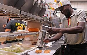 Lamin Ann bereitet an einer der beiden sogenannten Linien Burger zu. Die Bestellungen erscheinen auf einem Monitor, den die Mitarbeiter immer im Blick haben. Lamin Ann bereitet an einer der beiden sogenannten Linien Burger zu. Die Bestellungen erscheinen auf einem Monitor, den die Mitarbeiter immer im Blick haben.