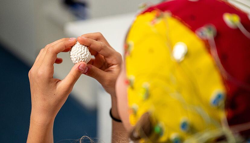 Eine Probandin tr&auml;gt eine EEG-Haube mit Elektroden f&uuml;r die Messung.