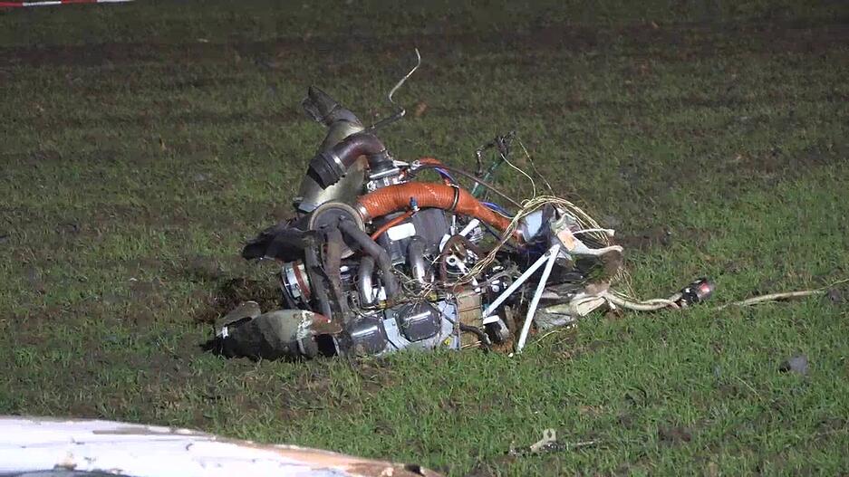 Tr&uuml;mmerteile des Kleinflugzeugs liegen auf einem Feld.
