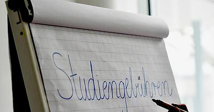 Eine junge Frau schreibt «Studiengebühren» an ein Flipchart. Foto: Jens Kalaene/Archiv