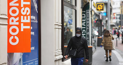 Fußgänger gehen an einer Teststation in der Innenstadt vorbei. Fußgänger gehen an einer Teststation in der Innenstadt vorbei.