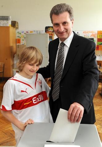 Der baden-w&uuml;rttembergische Ministerpr&auml;sident G&uuml;nther Oettinger (CDU) steckt am Sonntag neben seinem Sohn Alexander den Stimmzettel f&uuml;r die Europawahl in der Stuttgarter Vogelsang-Schule in die Wahlurne.