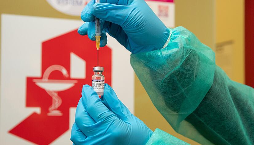 Eine Apothekerin zieht den Impfstoff Comirnaty vom Hersteller Biontech / Pfizer mit einer Spritze auf.