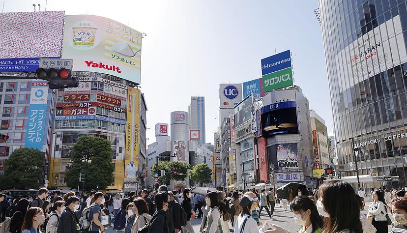 Menschen gehen in Japans Hauptstadt Tokio &uuml;ber eine Kreuzung.