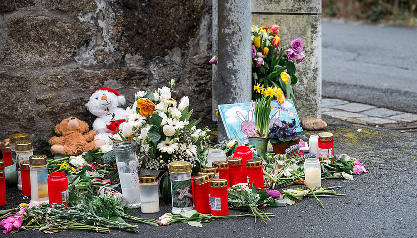 An einer Mauer vor dem Kinder- und Jugendhilfezentrum, in dem eine Zehnjährige tot aufgefunden wurde, liegen Blumen, Kuscheltiere und Kerzen.