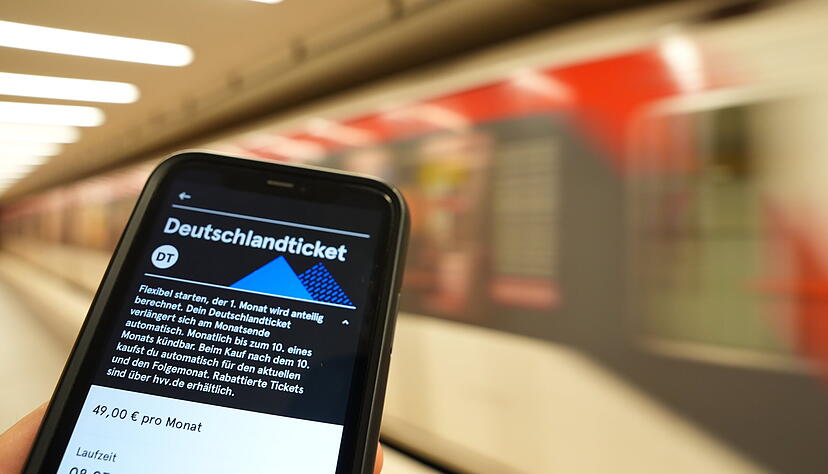 Ein Fahrgast hält ein Smartphone mit einem digitalen Deutschlandticket in der Hand.