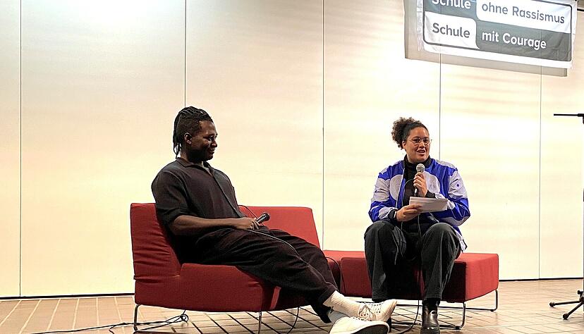 „Wir wissen viel zu wenig über Afrika“: Der „Afrofluencer“ Stève Hiobi in der Aula des Hartmanni-Gymnasiums im Gespräch mit der Lehrerin Nella Ruder. „Wir wissen viel zu wenig über Afrika“: Der „Afrofluencer“ Stève Hiobi in der Aula des Hartmanni-Gymnasiums im Gespräch mit der Lehrerin Nella Ruder.