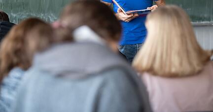 Ein Lehrer steht im Unterricht an der Tafel.
