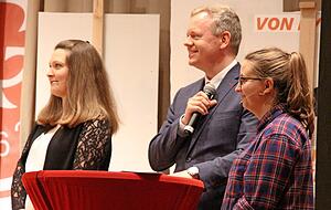 Landrat Matthias Neth moderiert die Weink&ouml;nig-Wahl. Unterst&uuml;tzt wird er von Karla Kolumna (l., Marleen H&auml;fele) und Rebecca Rebstock (Mathea Weinstock).