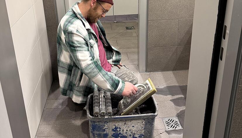 Fliesenleger Andreas Schilling bessert die Fugen in der Herrendusche aus. Fliesenleger Andreas Schilling bessert die Fugen in der Herrendusche aus.