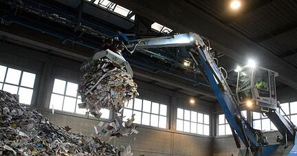 Ein Bagger verl&auml;dt Altpapier in einer Lagerhalle. Foto:&nbsp;Sina Schuldt/Archiv