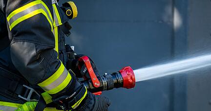 Ein Mitglied der Feuerwehr spritzt aus einem Schlauch mit Wasser.