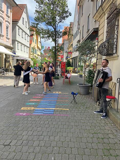 Zur Musik des Akkordeonspielers in der Nähe vom Oberen Tor in Öhringen legen sie ein Tänzchen hin. Da kommt gute Laune und Leichtigkeit auf. Die Musik des Akkordeonspielers entführt die Zuhörer nach Frankreich.
