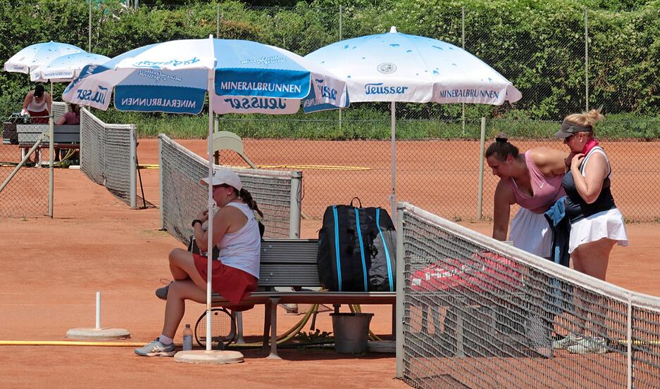 Die Tennis-Damen des TSV Künzelsau kühlen sich in den Spielpausen im Schatten mit nassen Handtüchern ab.