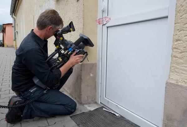 Ein Kameramann filmt die versiegelte Haustür der Wohnung.