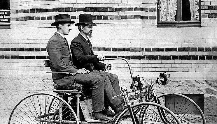 Wilhelm Maybach am Steuer des von ihm 1889 konstruierten Stahlradwagens; neben ihm Adolf Daimler, der Sohn von Gottlieb Daimler. Foto Mercedes Benz Classic