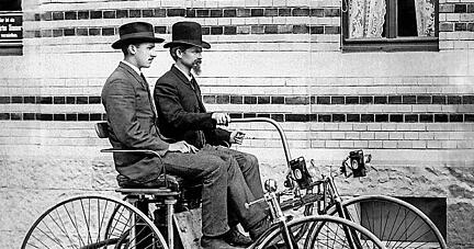 Wilhelm Maybach am Steuer des von ihm 1889 konstruierten Stahlradwagens; neben ihm Adolf Daimler, der Sohn von Gottlieb Daimler.
 Foto Mercedes Benz Classic