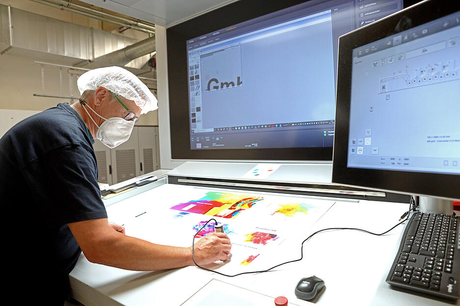 Thomas K&uuml;mmerer &uuml;berpr&uuml;ft die Druckdichte und -qualit&auml;t des hochaufl&ouml;senden Digitaldrucks.