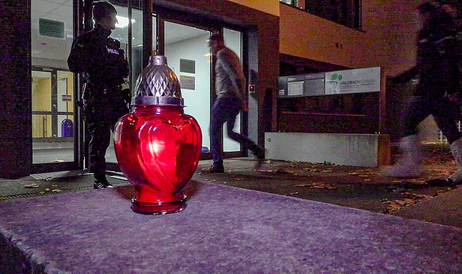 Nach dem Schusswaffenangriff an der Schule in Offenburg sind Kriminalpolizisten im Einsatz, im Vordergrund brennt eine Kerze. Nach dem Schusswaffenangriff an der Schule in Offenburg sind Kriminalpolizisten im Einsatz, im Vordergrund brennt eine Kerze.