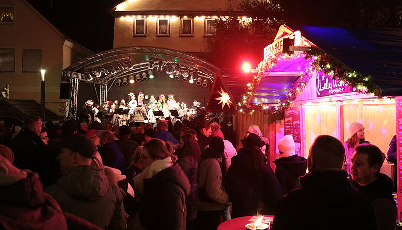Vor der Bühne stehen hunderte Menschen für die Eröffnung des „Advents am Schloss“, das Konzert von Stadtkapelle und Vokalensemble und die ersten Tassen Punsch und Glühwein.