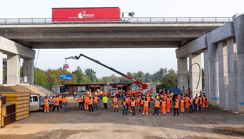 Oben rollt der Verkehr auf der A6, unten streiken Bauarbeiter von Hochtief. Zum ersten Warnstreik sind die Beschäftigten zusammengekommen. 
Foto: Mario Berger