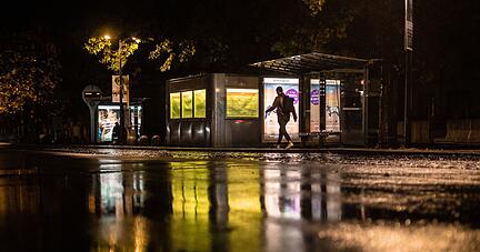 Werbeanzeigen leuchtet an einer Bushaltestelle  am Schlossplatz im Dunkeln.