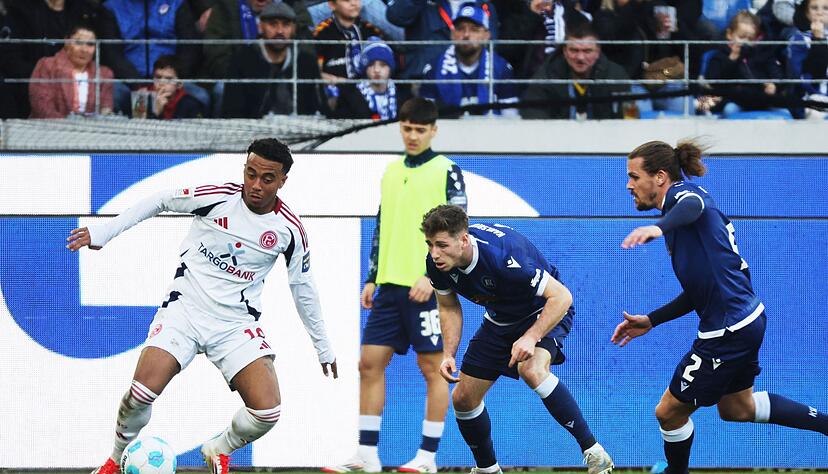 Die KSC-Spieler Leon Jensen (m) und Sebastian Jung (r) attackieren den Düsseldorfer Myron van Brederode (l). Die KSC-Spieler Leon Jensen (m) und Sebastian Jung (r) attackieren den Düsseldorfer Myron van Brederode (l).