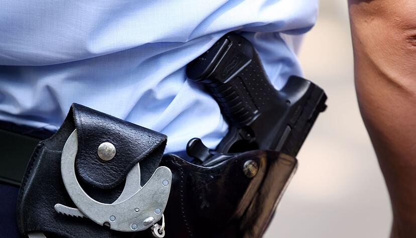 Ein Polizist trägt Handschellen und seine Dienstwaffe bei sich.