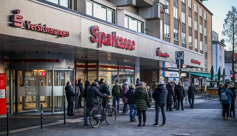 Nach einem Einbruch in den Tresorraum einer Bankfiliale in Gelsenkirchen warten Menschen vor dem Eingang auf Informationen.