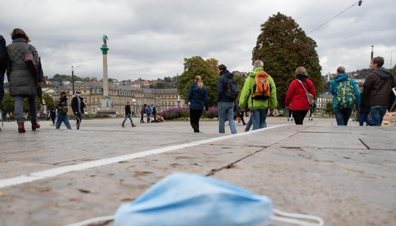 Ein Mundschutz liegt auf dem Stuttgarter Schlossplatz auf dem Boden, dahinter zahlreiche Passanten. Ein Mundschutz liegt auf dem Stuttgarter Schlossplatz auf dem Boden, dahinter zahlreiche Passanten.