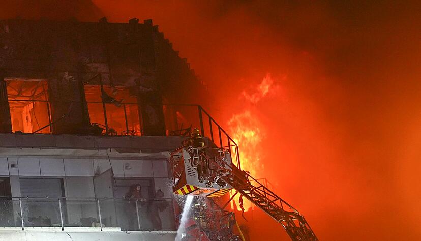 Feuerwehrleute retten zwei Menschen aus dem brennenden Hochhaus.