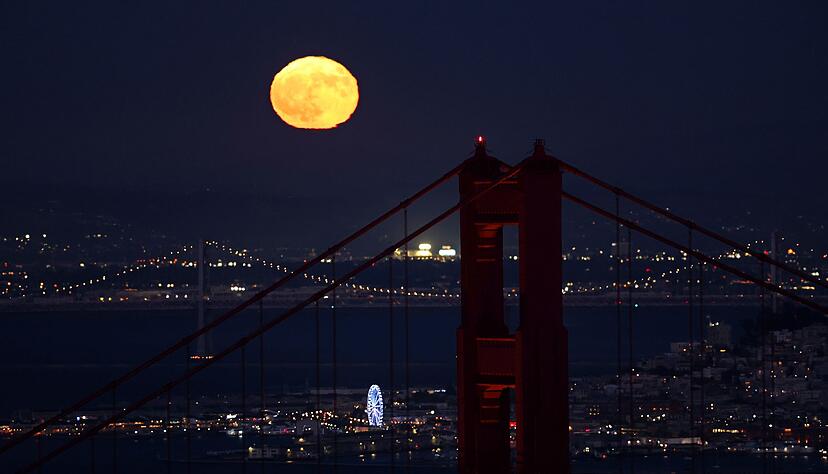 Hinter der Golden Gate Bridge ist am Himmel ein goldfarbener Vollmond zu sehen Hinter der Golden Gate Bridge ist am Himmel ein goldfarbener Vollmond zu sehen