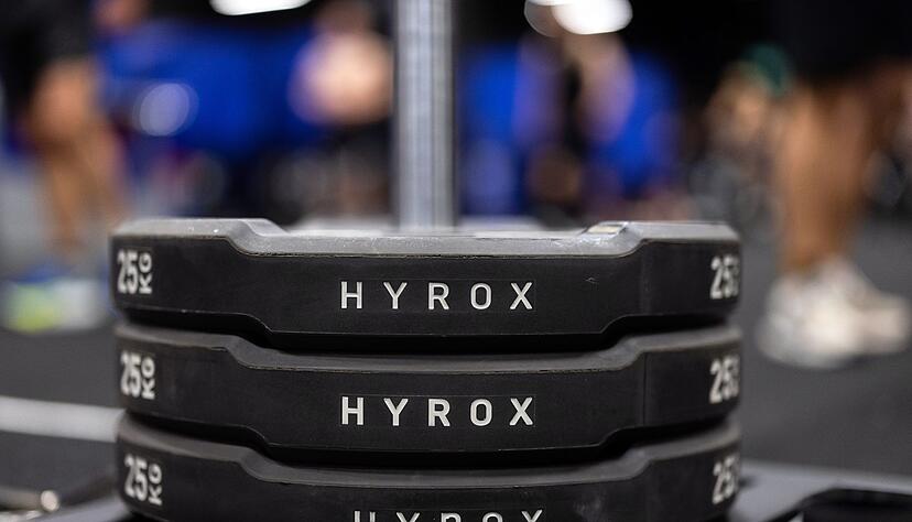 Hantelscheiben mit dem Schriftzug Hyrox an einem Messestand, wo wenig sp&auml;ter ein Lauf- und Workout-Wettbewerb stattfinden sollte.