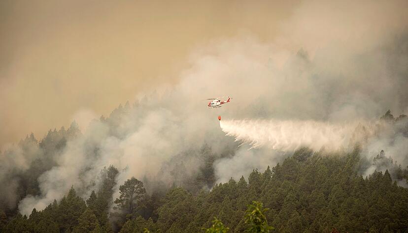 Ein Hubschrauber überfliegt einen Brand am Stadtrand von El Rosario während eines Löscheinsatzes. Ein Hubschrauber überfliegt einen Brand am Stadtrand von El Rosario während eines Löscheinsatzes.