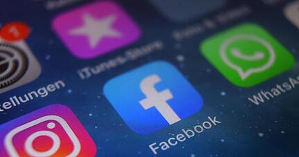 Auf dem Bildschirm eines Smartphones sind die Icons von Instagram, Facebook und WhatsApp zu sehen.