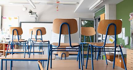 Stühle stehen in einem Klassenzimmer auf den Tischen. Stühle stehen in einem Klassenzimmer auf den Tischen.