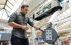 Produktionsleiter Manuel Knaus am flexibel ausfahrbaren Mediensystem Fly One, das vier Arbeitspl&auml;tze von der Decke mit Strom, Gas, Druckluft oder Daten versorgt.