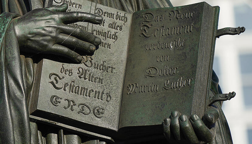 Das übersetzte „Neue Testament“ hält der Reformator Martin Luther in dem Lutherdenkmal auf dem Marktplatz in Lutherstadt Wittenberg.