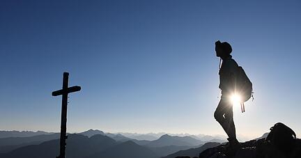 Eine Ausfl&uuml;glerin genie&szlig;t den Blick am Gipfelkreuz des Taubensteins.