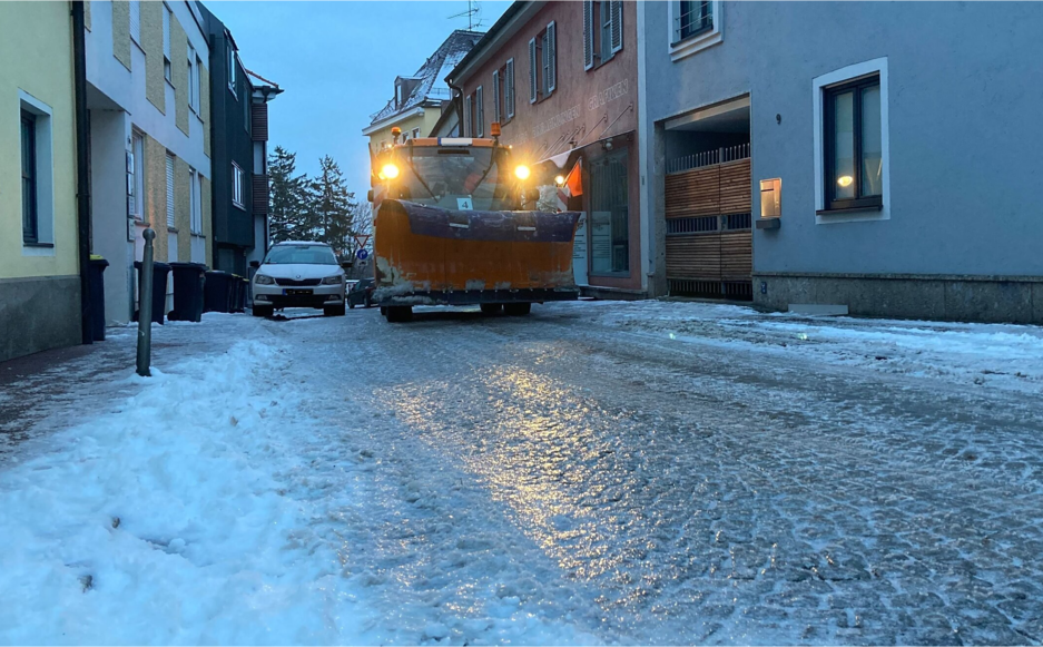 Ein Winterdienstfahrzeug fährt in Dachau (Bayern) auf eisglatter Straße durch die Stadt.
