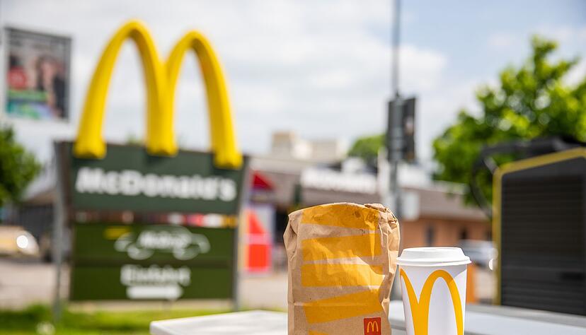 Eine McDonald's To-go-Tüte und ein dazugehöriger To-go-Becher stehen vor einer Tübinger McDonald's Filiale.