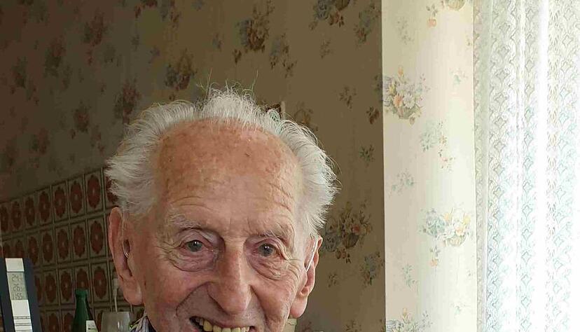 Karl Haidle sitzt an seinem 104. Geburtstag an einem Tisch und liest Zeitung.